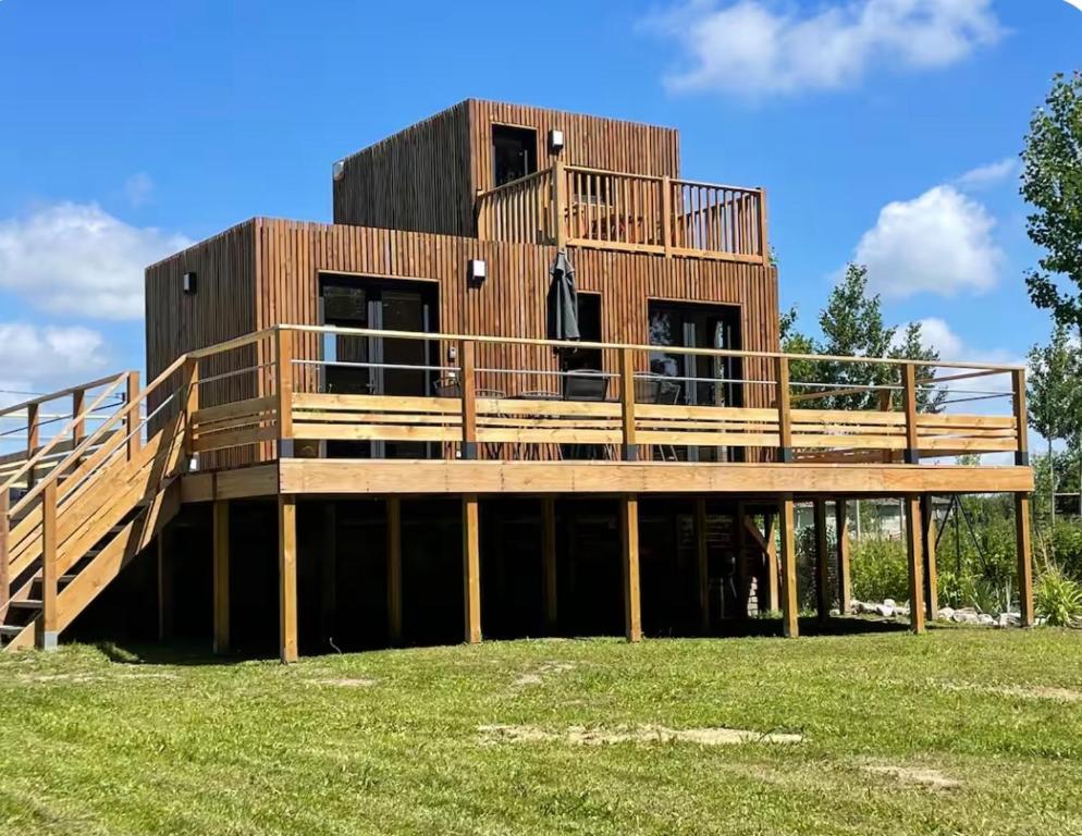 a house with a deck on a grass field at Au fil de l’eau, gîte nature in Abbécourt