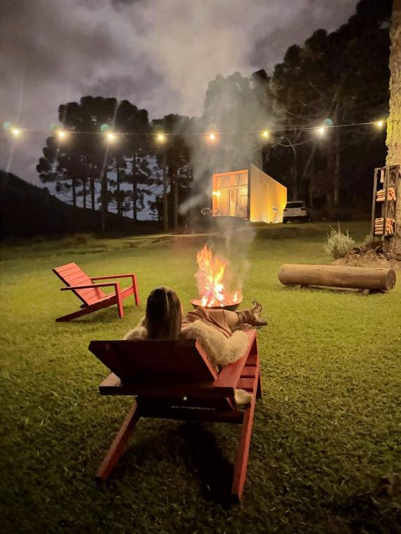 a woman laying on a bench next to a fire at Estalagem Santa Clara in Urubici