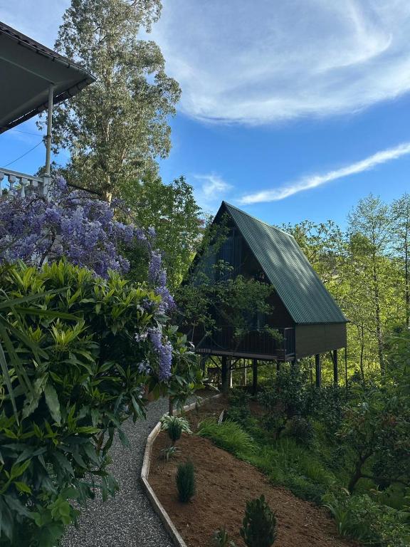 a house in the middle of a garden with purple flowers at Cottage Green Horizon Buknari in Buknari