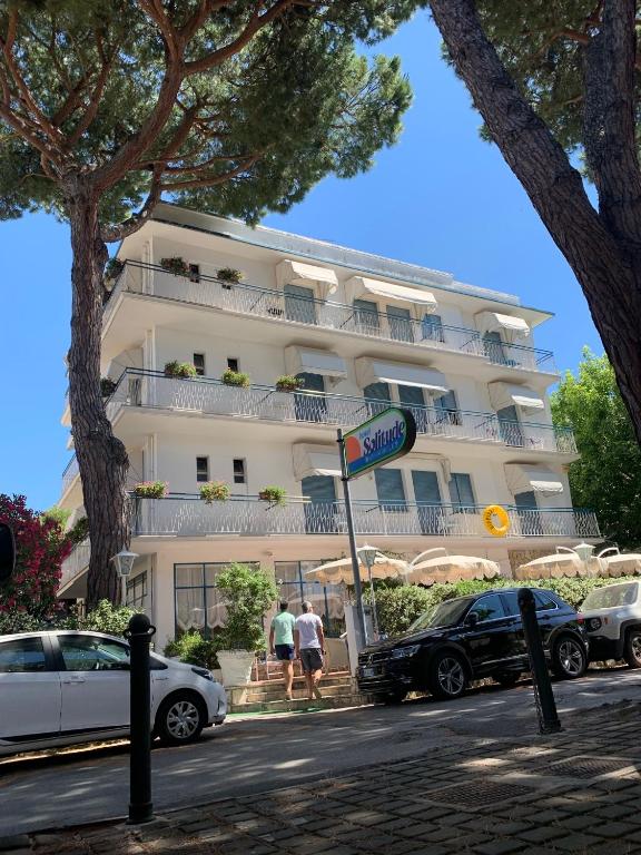 a large white building with cars parked in front of it at Hotel Solitude in Riccione