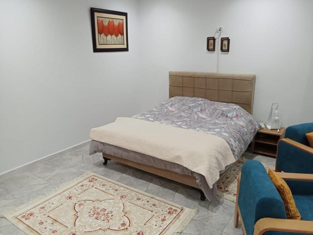 a bedroom with a bed and a blue chair at Résidence Rahma in Hammam Chott