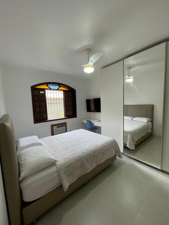 a bedroom with two beds and a glass wall at Quarto da Fran - perto da UFF in Niterói