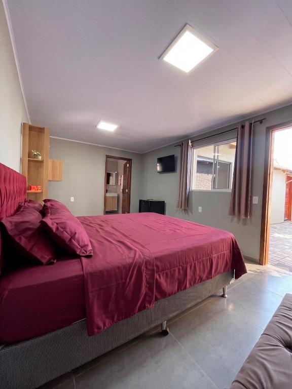 a bedroom with a large bed with a red bedspread at suíte perto da praia in Imbituba