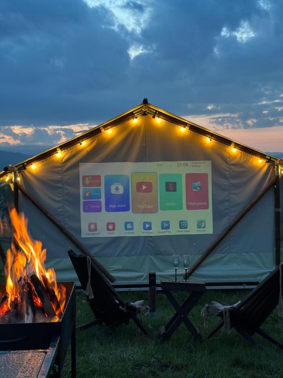 a tent with a fire in the grass with lights at Hutsul Glamp Панорамний вид Джакузі Best Sunset in Mykulychyn