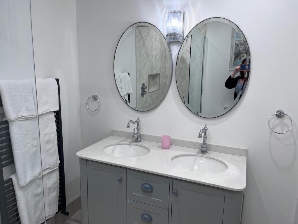 a bathroom with two sinks and two mirrors at Knockeven Hidden Gem in Waterford
