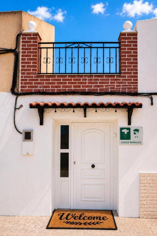 a white door on a building with a balcony at Casa Rural San Gregorio in Alcalá del Júcar