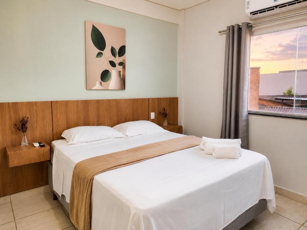 a bedroom with a large white bed with a window at Isa Flats in Janaúba
