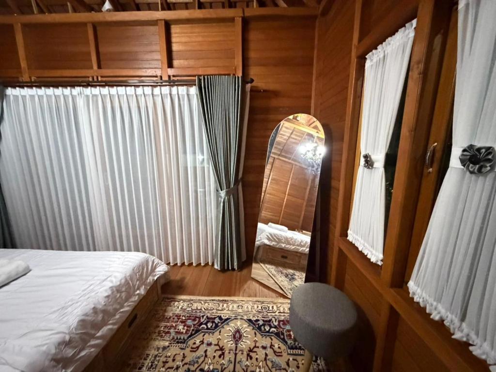 a bedroom with a bed and a mirror in a room at Pondok Nisya in Sawan