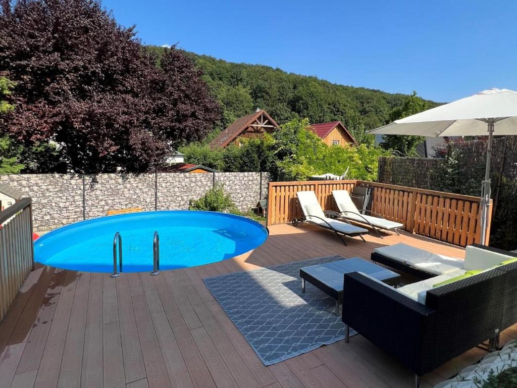 a pool on a deck with chairs and an umbrella at Wienerwaldblick in Mauerbach