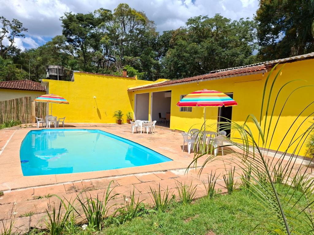 a yellow house with a swimming pool and an umbrella at Chácara Solar de Jarinu in Jarinu