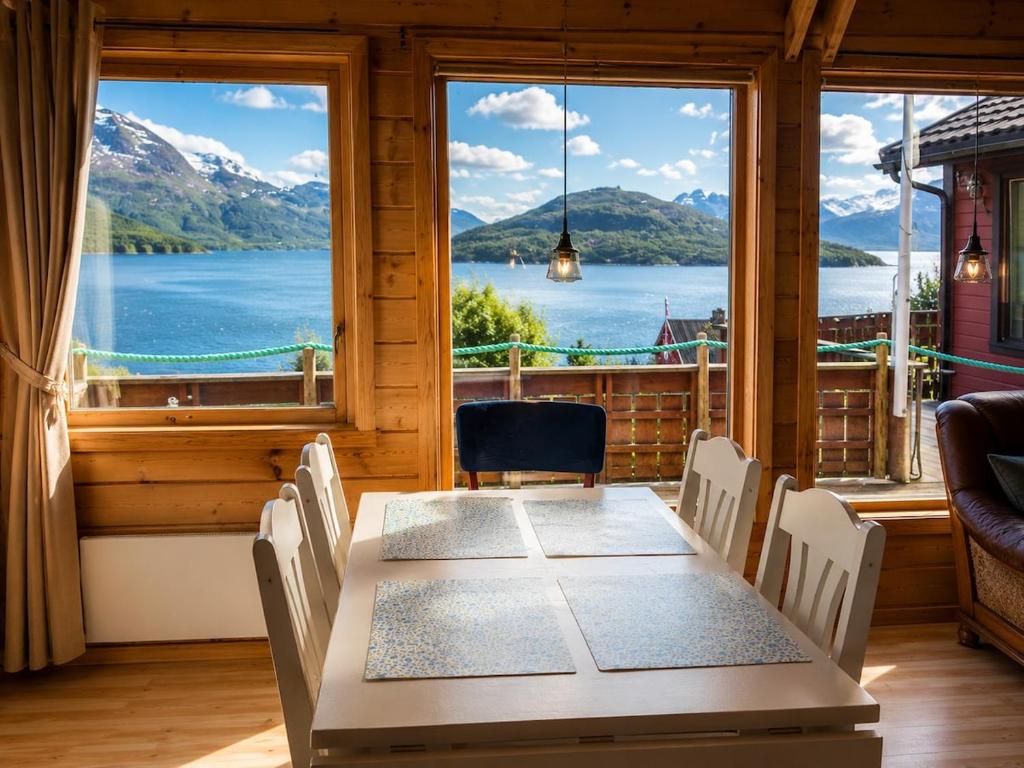 a table and chairs in a room with a view of a lake at Ryten View Retreat in Hovdan