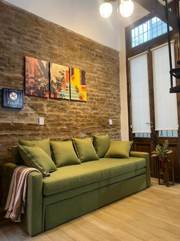 a green couch in a room with a brick wall at Loft con patio frente a Mercado San Telmo, 2 baños in Buenos Aires