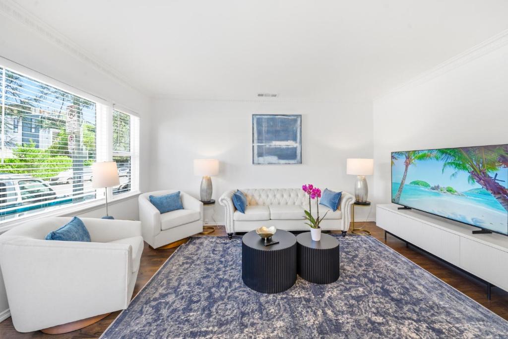 a living room with white furniture and a large screen tv at Venice Venice in Los Angeles