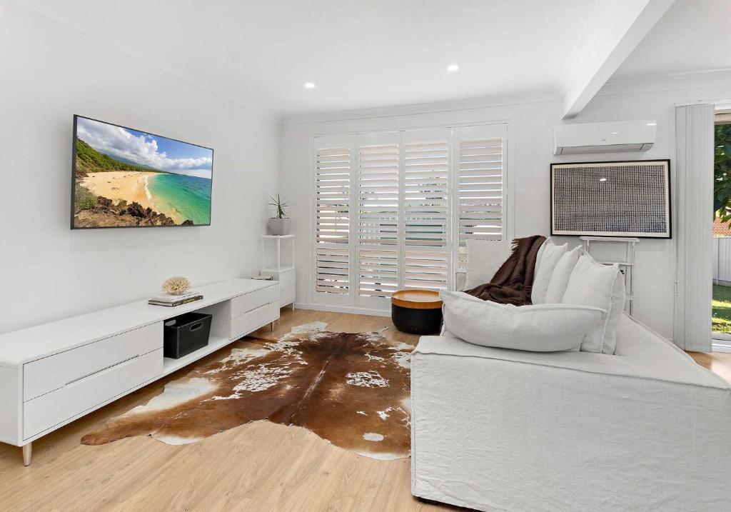 a white living room with a couch and a table at Flinders Hideaway in Shellharbour