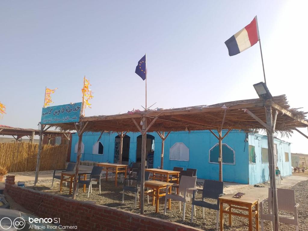 a blue building with tables and chairs and a flag at Hamata House Camp in Abū Ghuşūn