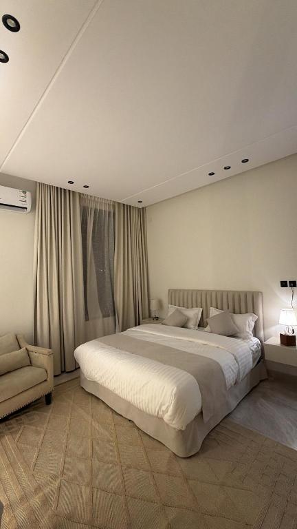 a bedroom with a large white bed and a chair at Velora Suites in Abha