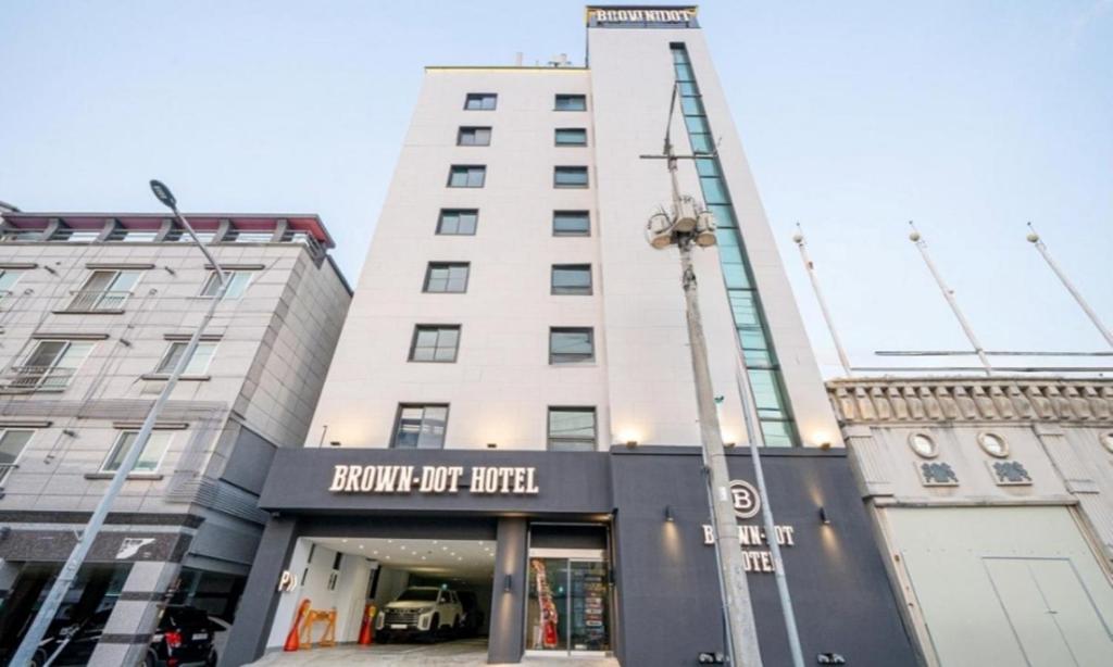 a tall white building with a sign in front of it at Brown Dot Hotel NamGumi in Yangji-mal