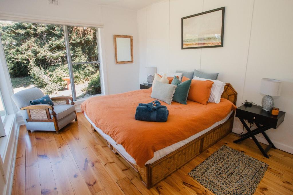 a bedroom with a large bed with an orange blanket at WattleJack Cottage in Kingscote