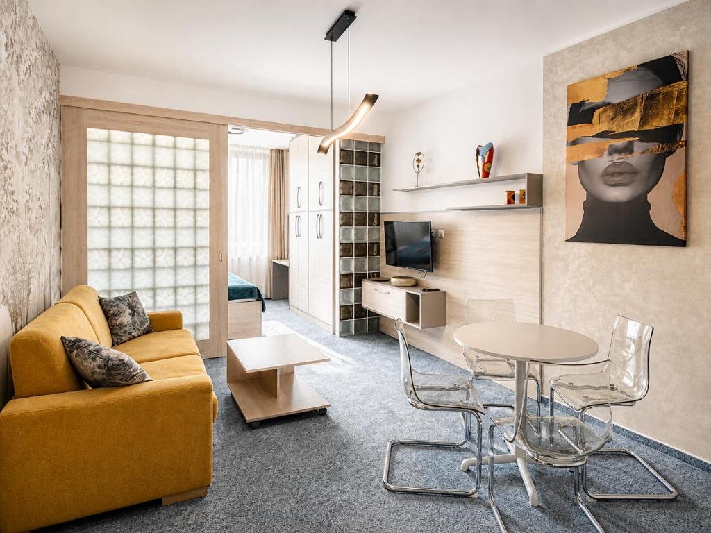 a living room with a yellow couch and a table at Apartment Elegance Hrebienok in Starý Smokovec