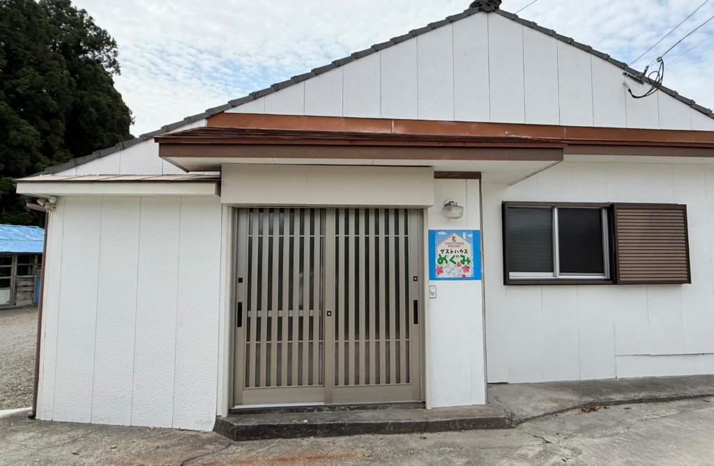 a white house with a door and a window at ゲストハウスめぐみ in Iizuka