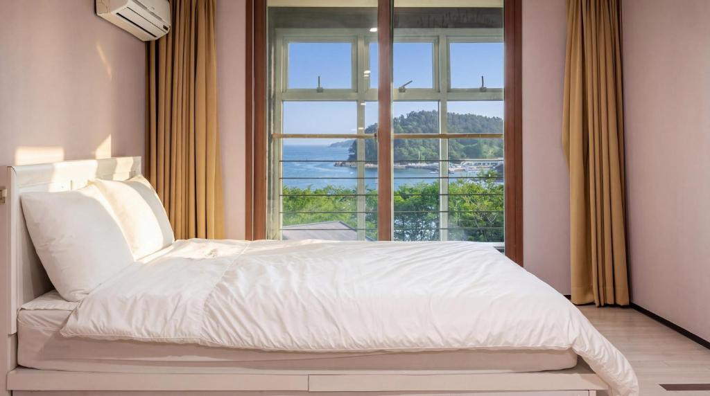 a bedroom with a bed and a large window at Geoje Erion Pet-Friendly Pension in Geoje