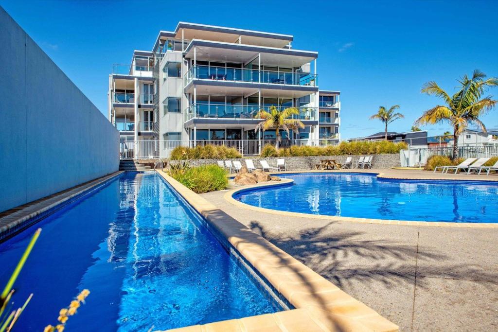 a resort swimming pool with a building in the background at Ohope Beach Resort in Ohope Beach