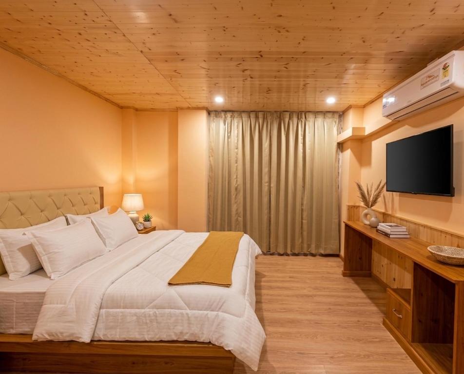 a bedroom with a large bed and a flat screen tv at Mist Valley By Zenia in Fagu