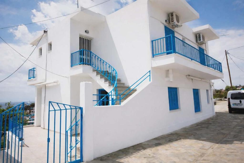 a white building with blue stairs on it at George Rooms in Votsi