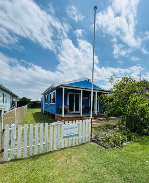 a blue house with a fence in a yard at Bonnydoon at Hat Head - 5 Oak Street in Hat Head