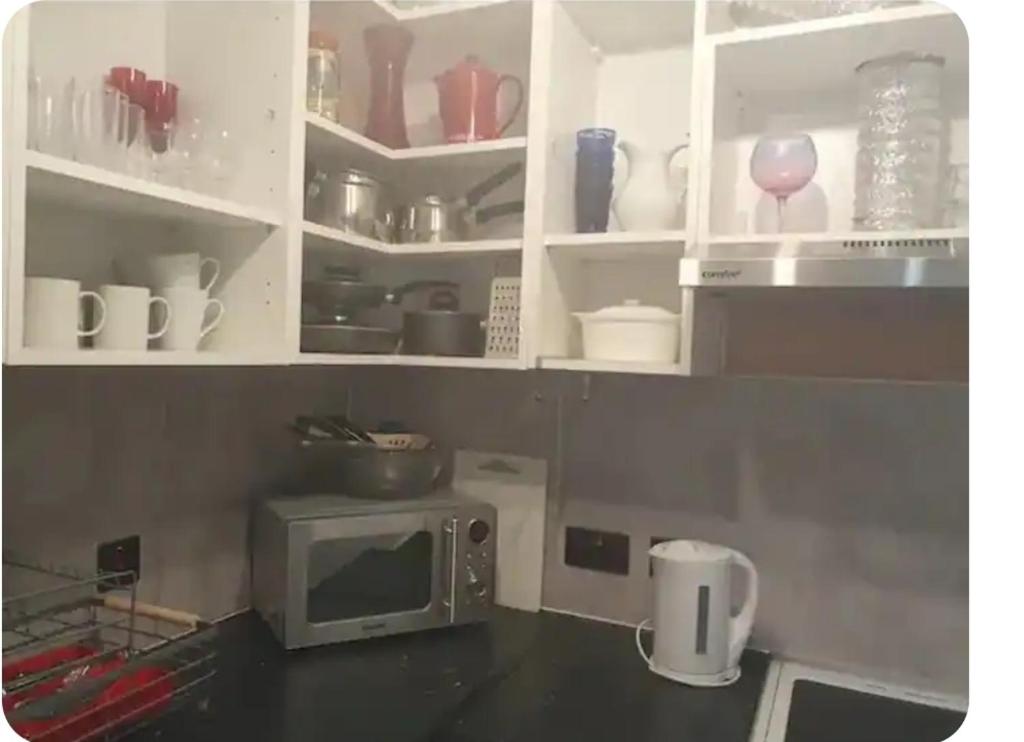 a kitchen with white cabinets and a microwave at Star Apartment in Guildford