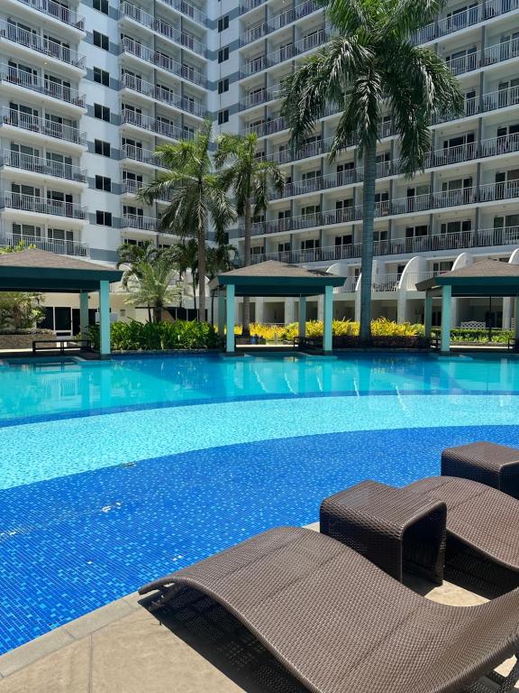a swimming pool with two lounge chairs in front of a building at Shell Residences MOA by Joseph in Manila