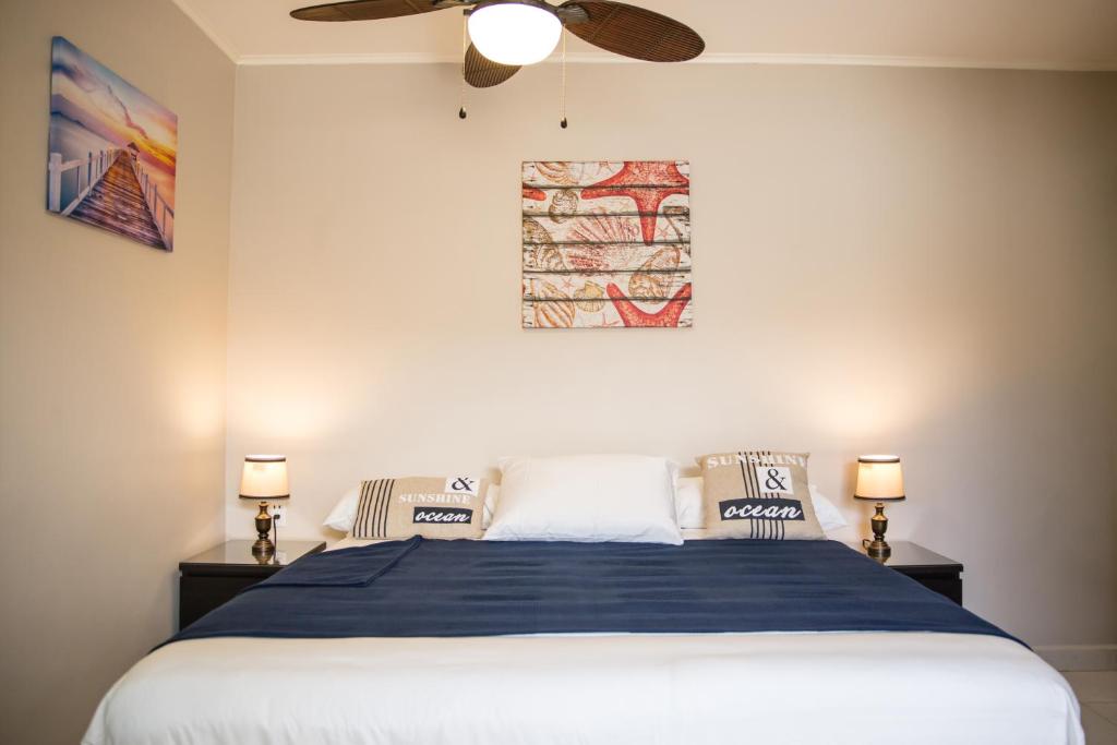a bedroom with a bed and a ceiling fan at The Pier Beach Inn & Suites in Willemstad