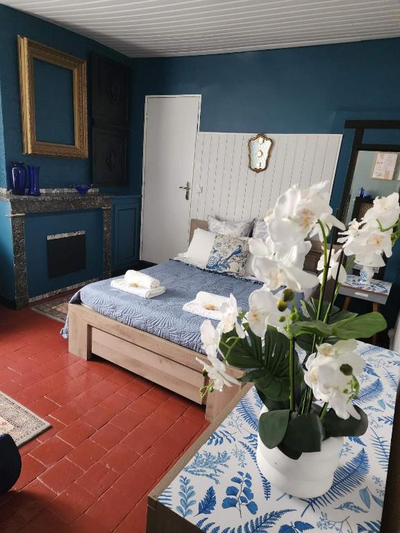 a bedroom with a bed and a vase with white flowers at Marie-Claire la grillade in Briare