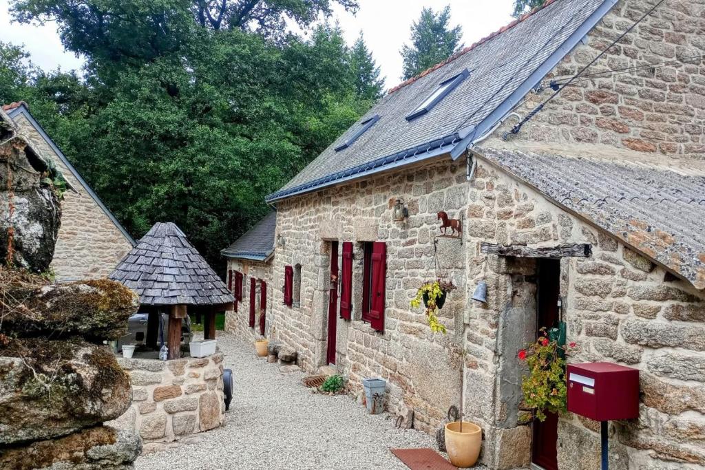 an old stone building with red doors and windows at Le Breizh des Bois in Le Faouët