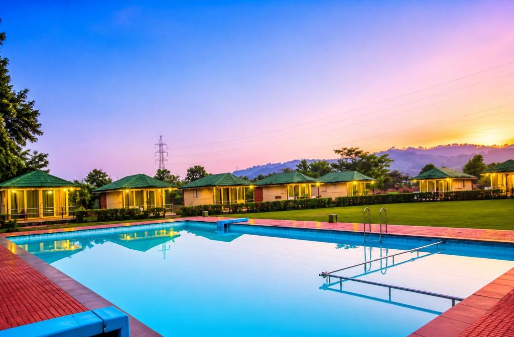 a villa with a swimming pool at sunset at Nature Trails Durshet, Khopoli in Khopoli