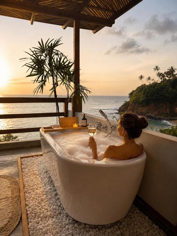 a woman sitting in a bath tub with a glass of wine at Ocean Bliss by Sugar Coliving in Weligama