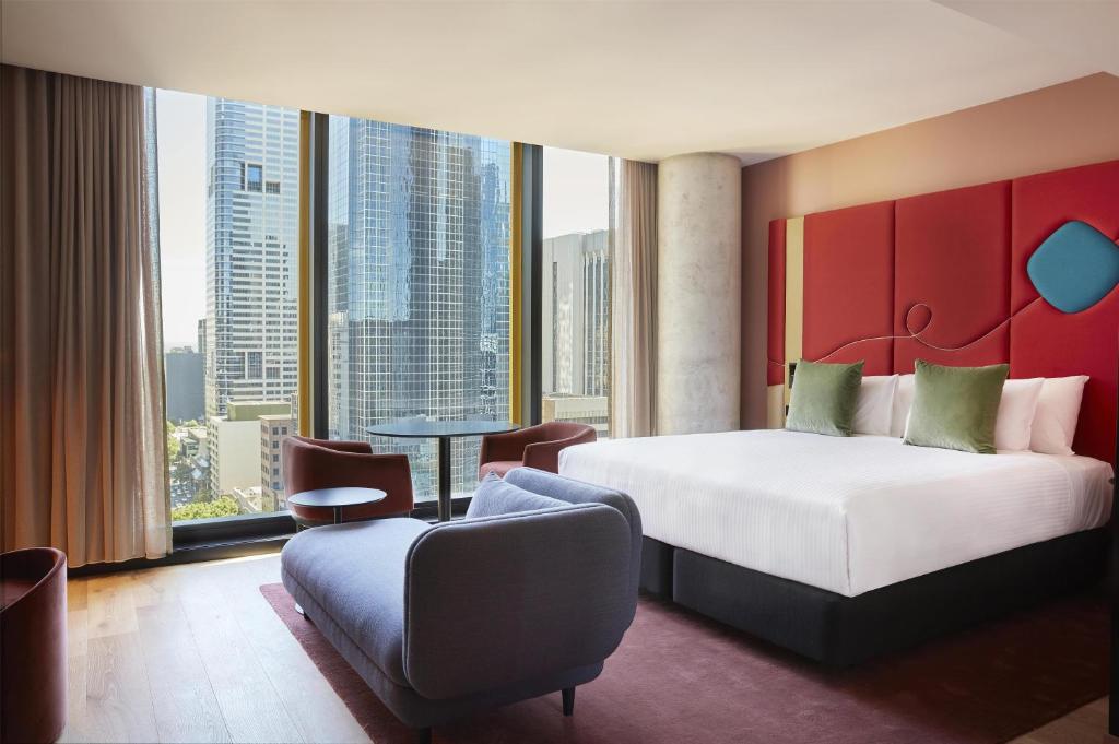 a hotel room with a bed and a large window at Quincy Hotel Melbourne in Melbourne