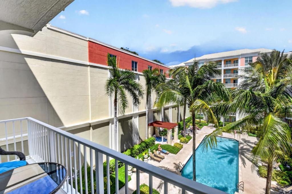 a balcony with a swimming pool and palm trees at Moorings Pool Overview Resort in Lantana