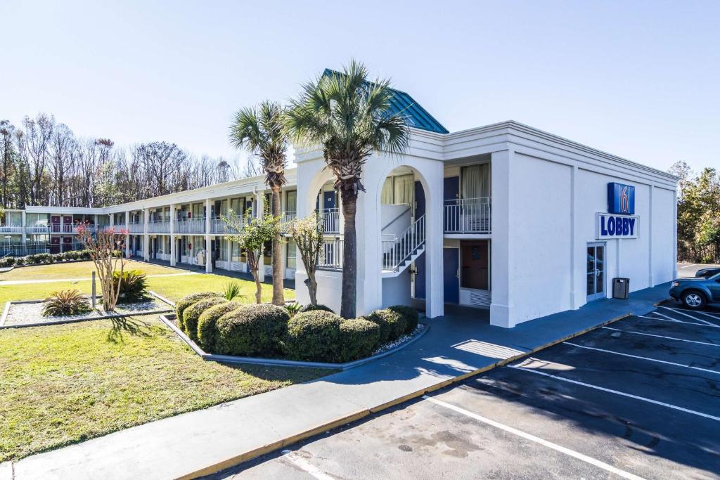 un grand bâtiment blanc avec des palmiers et un parking dans l'établissement Motel 6-Townsend, GA, à Eulonia