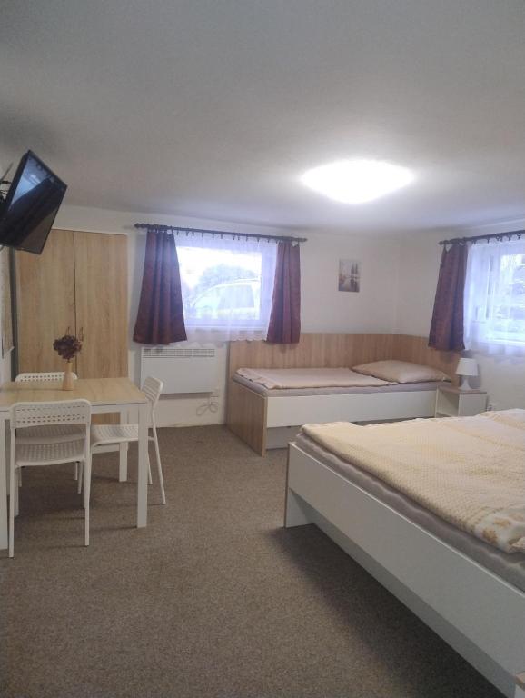 a bedroom with two beds and a table and a desk at Ubytování U Jindřicha ll in Weissbach