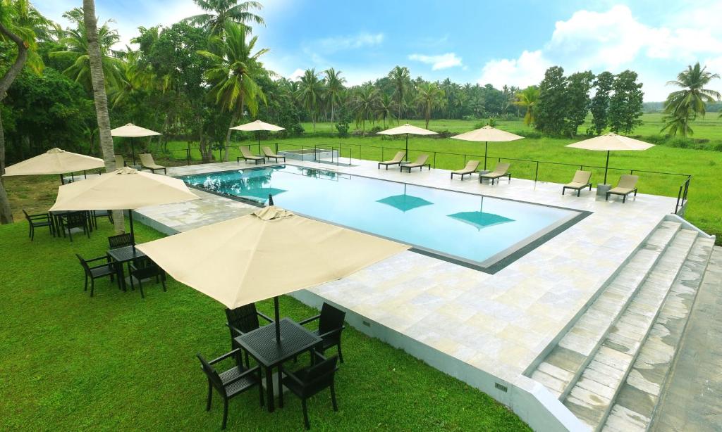 an overhead view of a pool with chairs and umbrellas at Miracle Resorts & Villas in Polonnaruwa