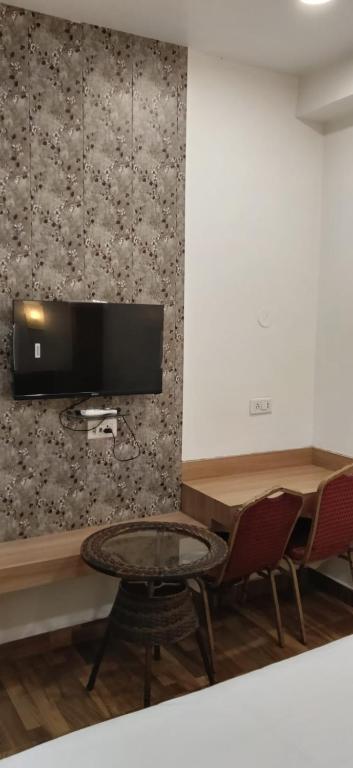 a room with a table and a tv on a wall at Hotel Midtown in Rourkela