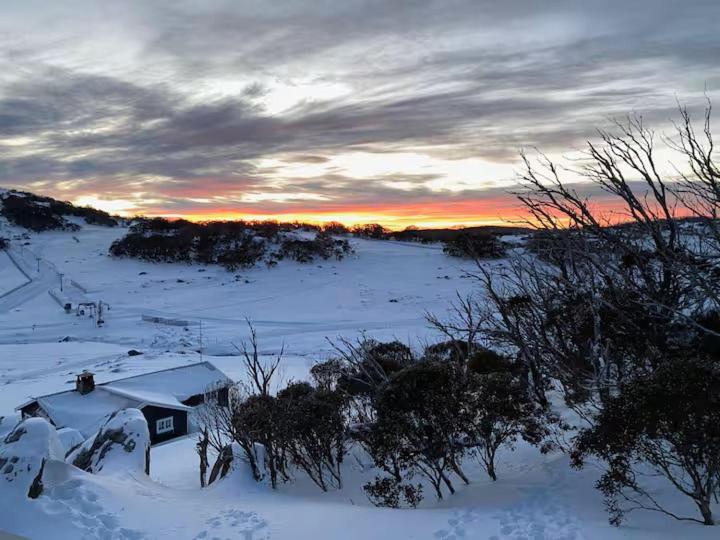 a field covered in snow with a sunset in the background at Illabunda Ski Lodge in Perisher Valley