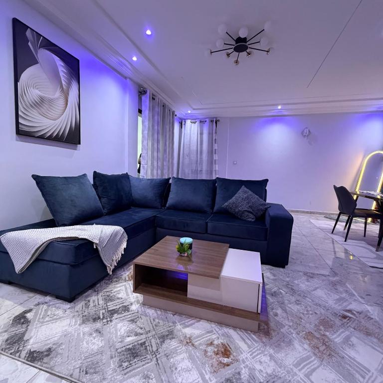 a living room with a blue couch and a table at Egel Appartement in Yaoundé