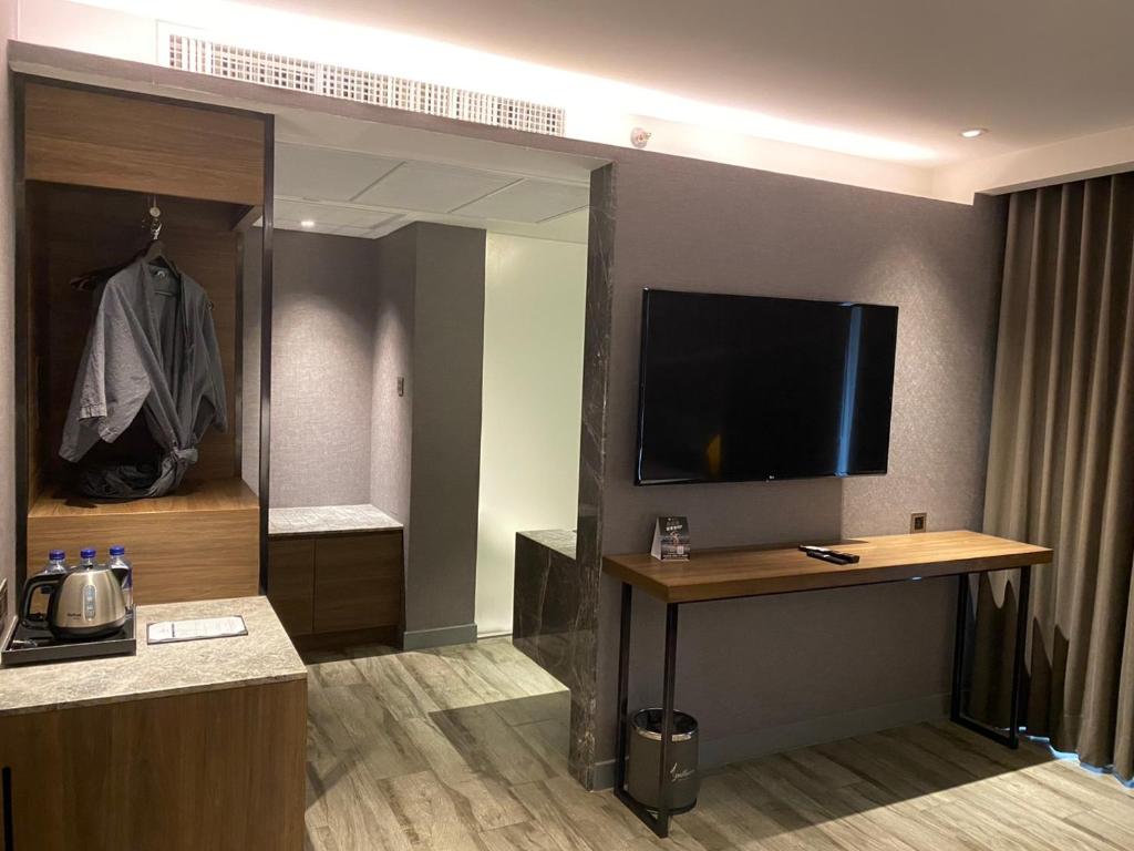A compact room work area with a wall-mounted TV, narrow desk, minibar counter, and wardrobe.