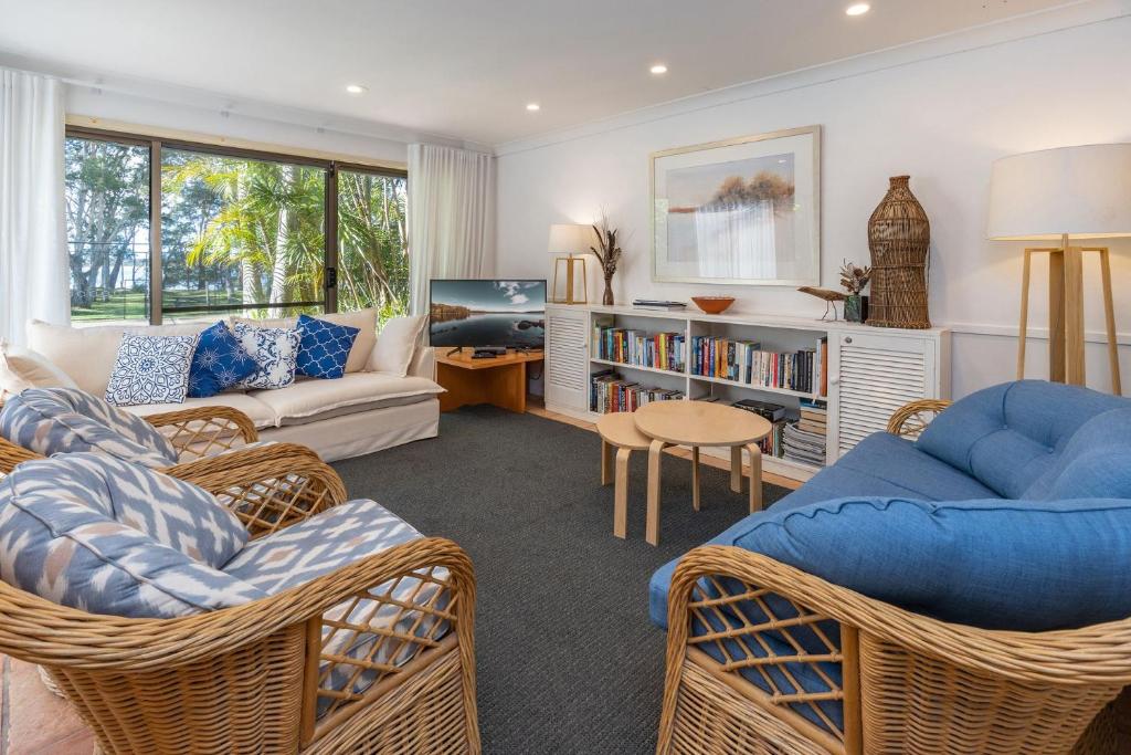 a living room with wicker chairs and a blue couch at Sandpiper 21 in Smiths Lake