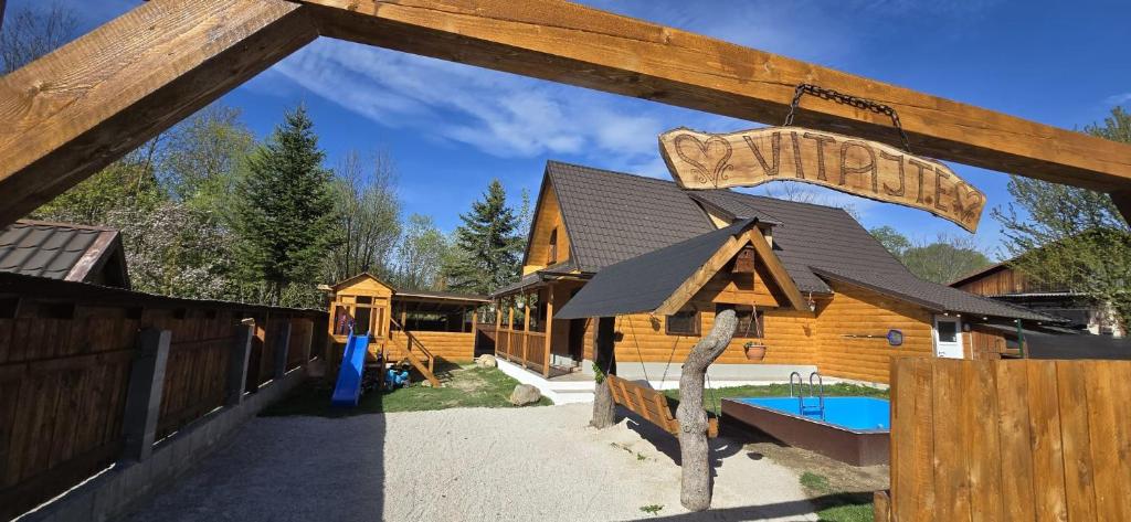 a log cabin with a sign on a fence at Farma pod Skalkou in Heľpa