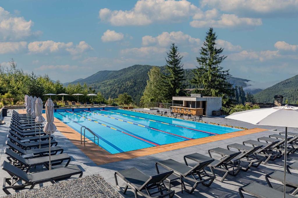 a large swimming pool with lounge chairs and umbrellas at Koruna in Tatariv