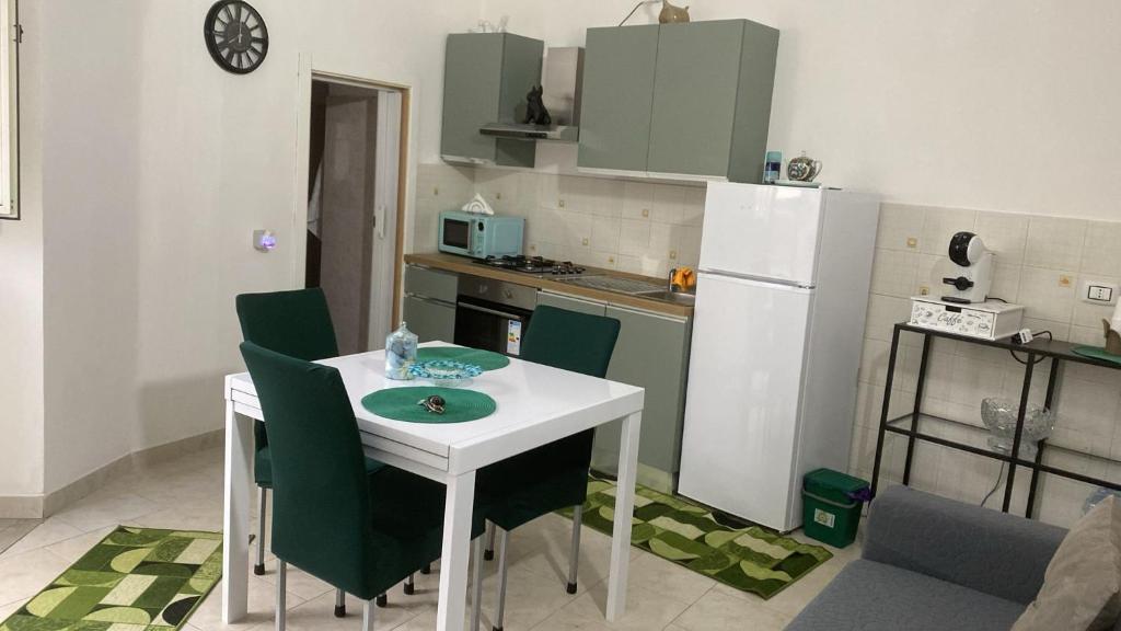 a small kitchen with a white table and green chairs at Casa di Claudio in Arpaia
