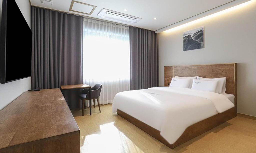 a bedroom with a large white bed and a desk at Hotel Grand Bay Boryeong in Boryeong